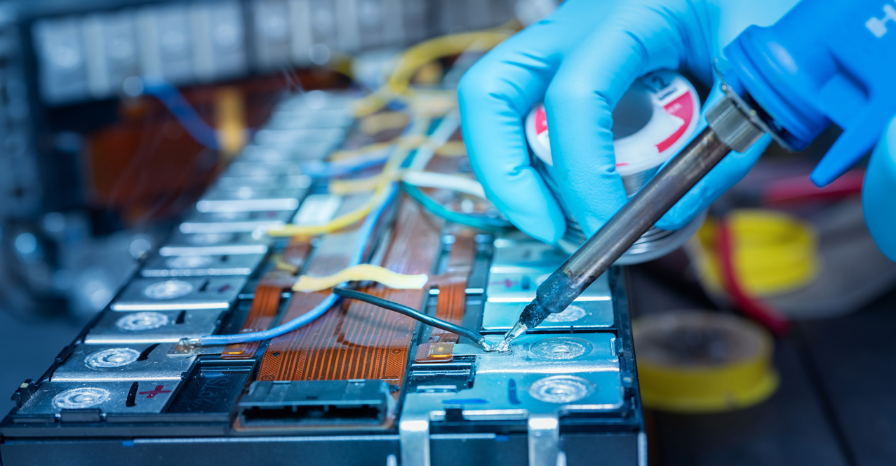 gloved hands soldering an electric vehicle battery