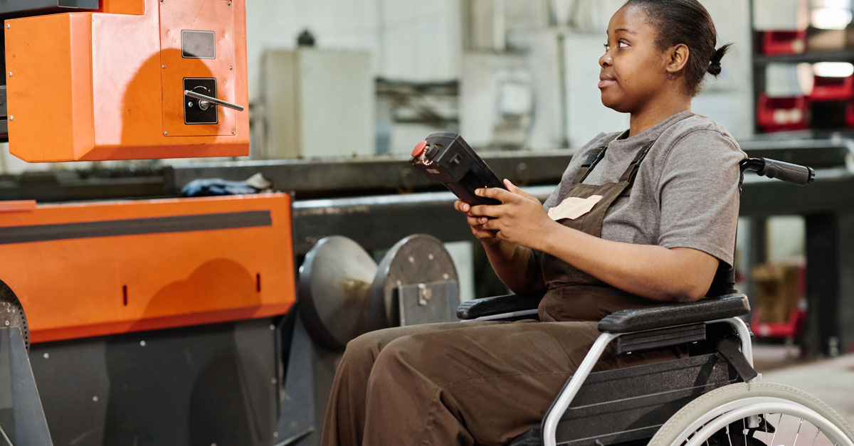 worker in wheelchair at factory machine